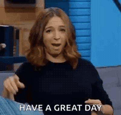 A Woman Is Sitting On A Couch With Her Mouth Open And Pointing At The Camera While Saying `` Have A Great Day '' . GIF
