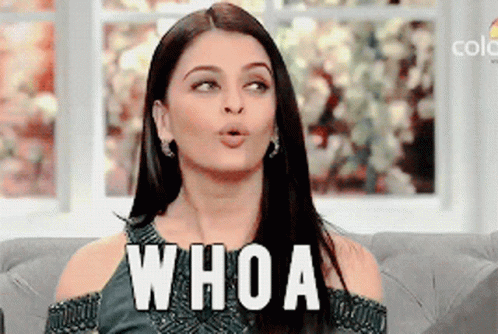 A Woman Is Sitting On A Couch With Her Mouth Open And The Word Whoa Written On Her Face GIF