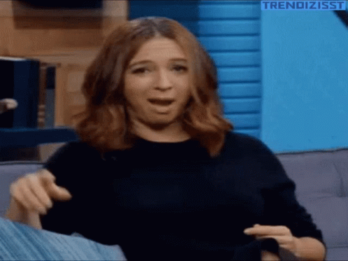 A Woman Is Sitting On A Couch With Her Mouth Open And The Words Trendizisst On The Bottom Right GIF