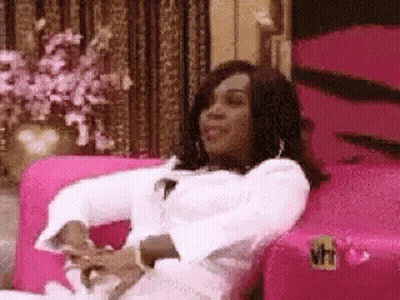 A Woman Is Sitting On A Pink Couch With Her Arms Crossed . GIF