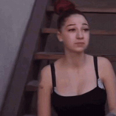 A Woman Is Sitting On A Set Of Stairs With Her Eyes Closed . GIF