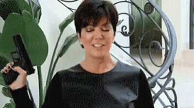 A Woman Is Sitting On A Staircase Holding A Gun In Her Hand . GIF