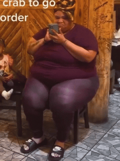 A Woman Is Sitting On A Stool Looking At Her Phone With The Words " Crab To Go Order " Written Above Her GIF
