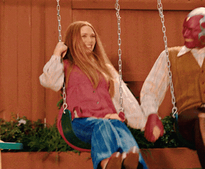 A Woman Is Sitting On A Swing Next To A Man In A Mask GIF
