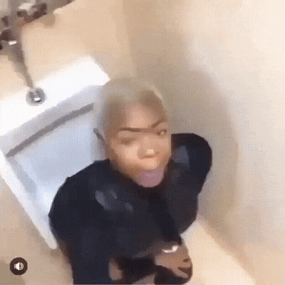 A Woman Is Sitting On A Toilet In A Bathroom With Her Tongue Out . GIF