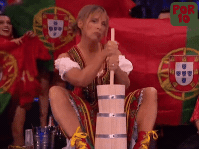 A Woman Is Sitting On A Wooden Barrel With A Flag In The Background GIF