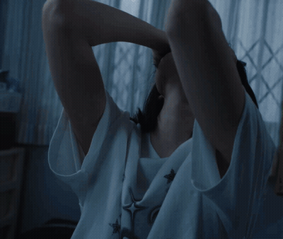 A Woman Is Sitting On An Escalator Holding Her Head In Pain GIF