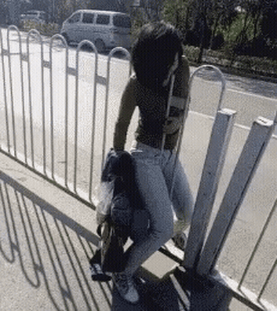 A Woman Is Sitting On Another Woman 'S Lap On A Sidewalk . GIF