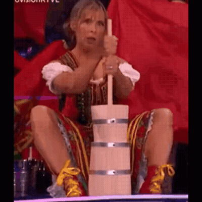 A Woman Is Sitting On The Floor Holding A Wooden Bucket And A Wooden Stick . GIF