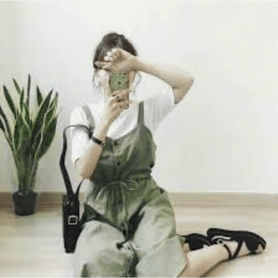 A Woman Is Sitting On The Floor Taking A Selfie With Her Cell Phone . GIF