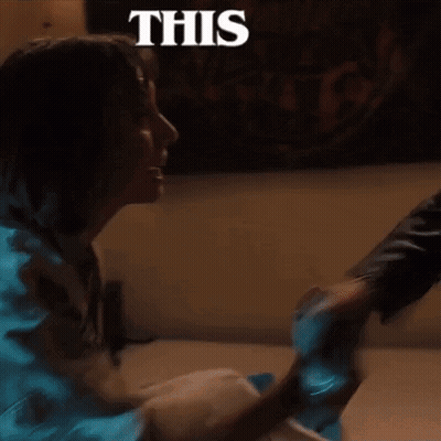 A Woman Is Sitting On The Floor With A Man Holding Her Hand And A Sign That Says This . GIF