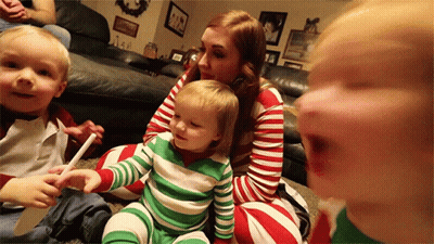A Woman Is Sitting On The Floor With Two Children Wearing Striped Pajamas GIF
