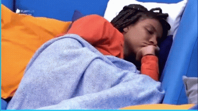 A Woman Is Sleeping In A Bed With A Blue Blanket On Her Head . GIF