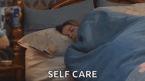 A Woman Is Sleeping In A Bed With The Words Self Care Written Above Her GIF