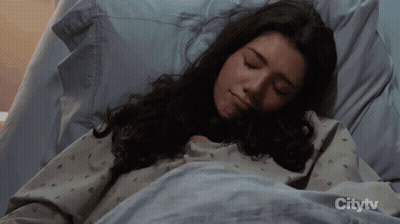 A Woman Is Sleeping In A Hospital Bed With Citytv On The Bottom GIF