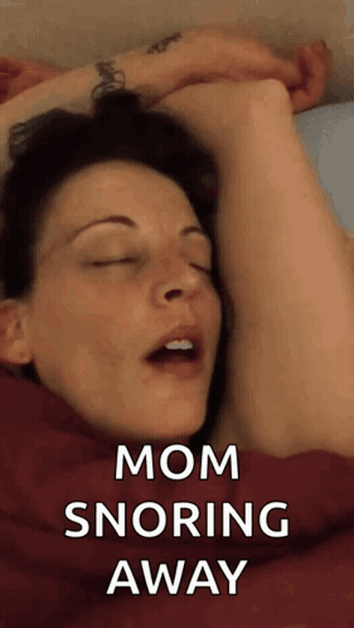A Woman Is Sleeping In Bed With Her Eyes Closed And The Words Mom Snoring Away Above Her . GIF