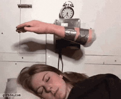 A Woman Is Sleeping In Front Of An Alarm Clock And A Hand Is Sticking Out Of It GIF