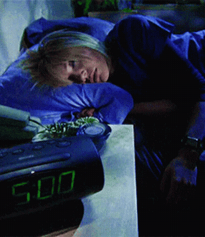 A Woman Is Sleeping Next To An Alarm Clock That Shows The Time As 5:00 GIF