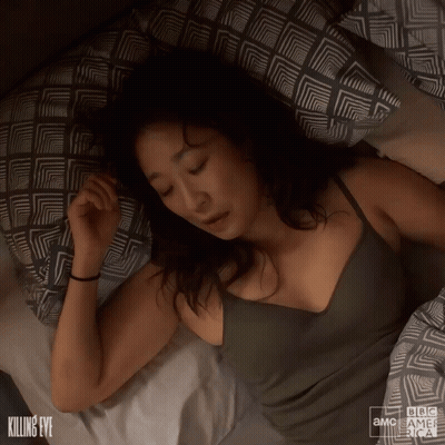 A Woman Is Sleeping On A Bed With A Bbc America Logo GIF