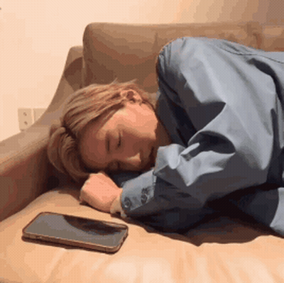 A Woman Is Sleeping On A Couch With A Cell Phone Next To Her . GIF