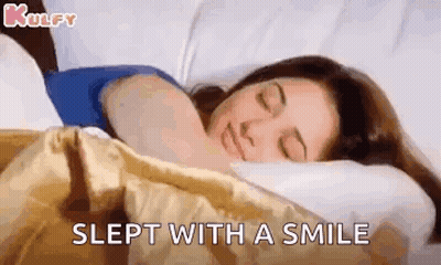 A Woman Is Sleeping With A Smile On Her Face . GIF