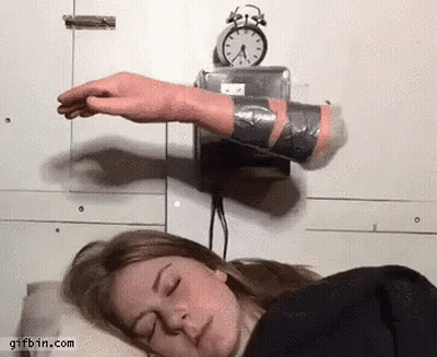A Woman Is Sleeping With Her Eyes Closed And A Clock On The Wall Above Her Head GIF