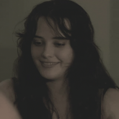 A Woman Is Smiling And Holding A Cell Phone GIF
