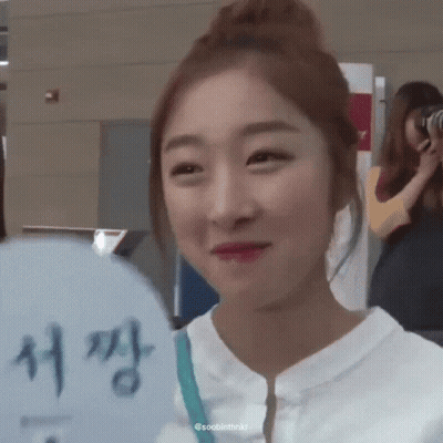 A Woman Is Smiling And Holding A Fan With Chinese Writing On It GIF