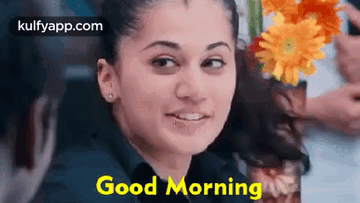 A Woman Is Smiling And Holding A Vase Of Flowers In Her Hand . GIF