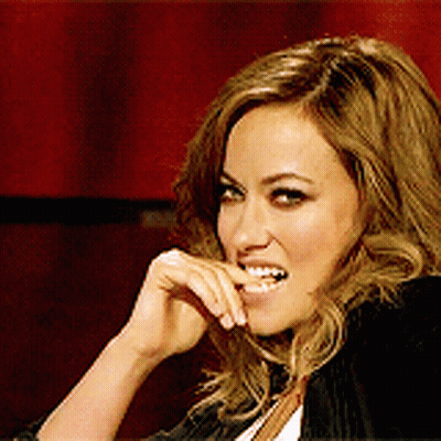 A Woman Is Smiling And Holding Her Hand To Her Face GIF