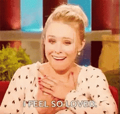 A Woman Is Smiling And Holding Her Hands To Her Chest . GIF