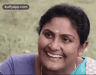 A Woman Is Smiling And Looking At The Camera While Wearing A Blue Shirt And A Blue Saree . GIF