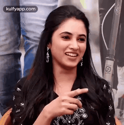 A Woman Is Smiling And Pointing At The Camera . GIF