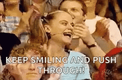 A Woman Is Smiling And Pushing Through A Crowd Of People In A Stadium . GIF