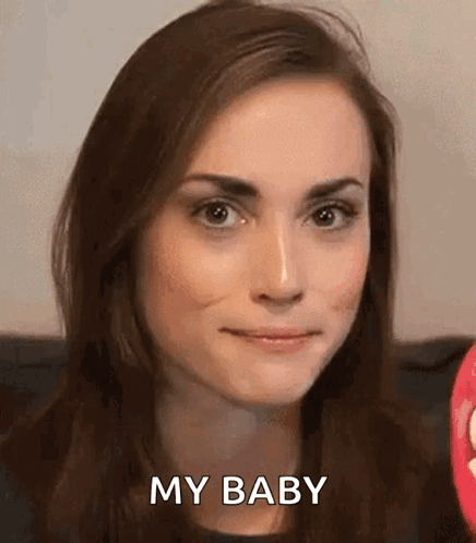 A Woman Is Smiling And Saying `` My Baby '' While Sitting On A Couch . GIF
