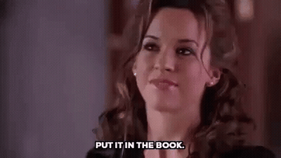 A Woman Is Smiling And Saying `` Put It In The Book '' While Looking At The Camera . GIF