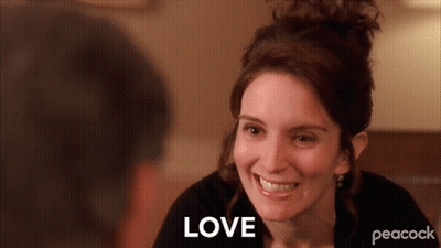 A Woman Is Smiling And The Word Love Is Visible Behind Her GIF