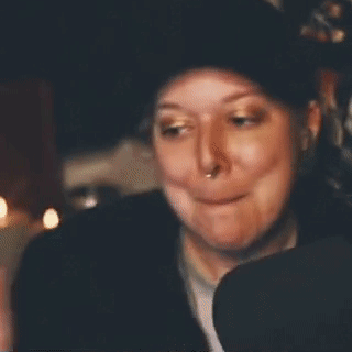 A Woman Is Smiling And Waving Her Hand In Front Of A Sign That Says Bye-Bye . GIF