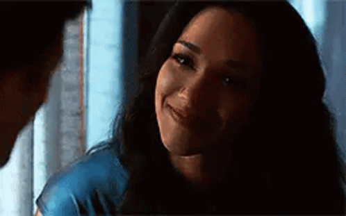 A Woman Is Smiling At A Man In A Dark Room While Looking At Him . GIF
