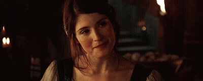 A Woman Is Smiling In A Dark Room With Candles In The Background GIF