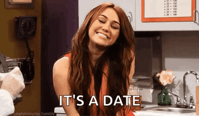 A Woman Is Smiling In A Kitchen With The Words `` It 'S A Date '' Written On Her Face . GIF