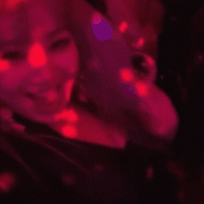 A Woman Is Smiling In A Red Light GIF