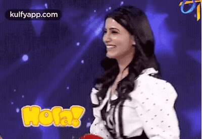 A Woman Is Smiling In Front Of A Blue Background While Holding A Red Balloon . GIF