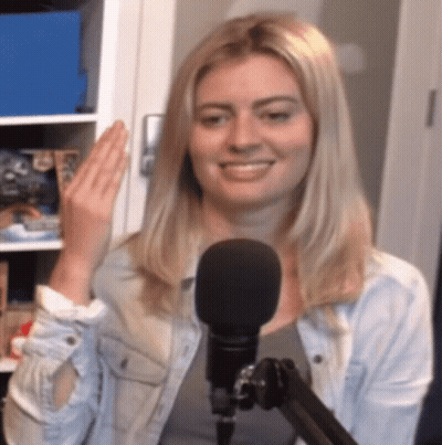A Woman Is Smiling In Front Of A Microphone And Waving GIF