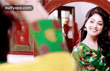 A Woman Is Smiling In Front Of A Mirror In A Room . GIF