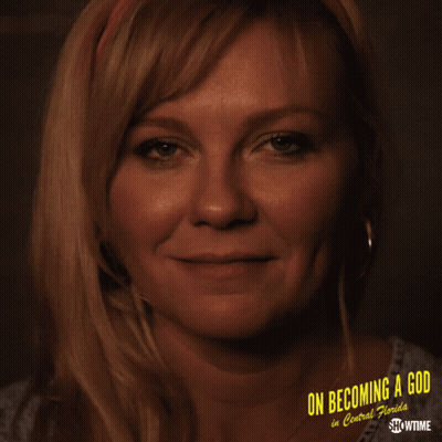 A Woman Is Smiling In Front Of A Poster That Says On Becoming A God In Central Florida GIF