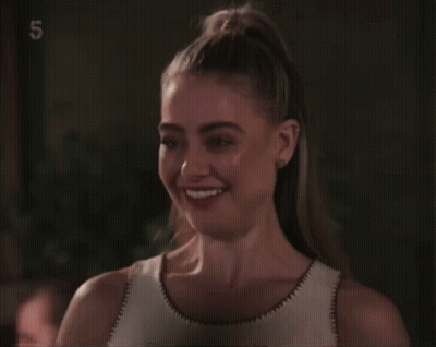 A Woman Is Smiling In Front Of A Screen With The Number 5 On It GIF
