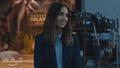 A Woman Is Smiling In Front Of A Sign For Prime Video GIF