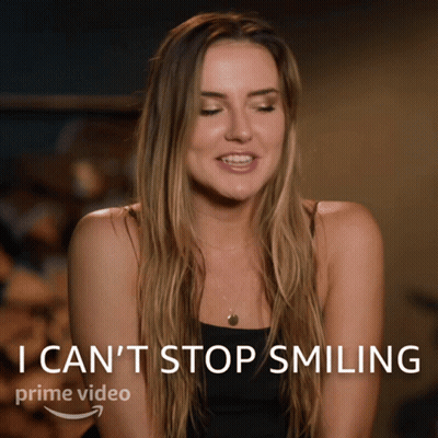 A Woman Is Smiling In Front Of A Sign That Says I Can 'T Stop Smiling Prime Video GIF