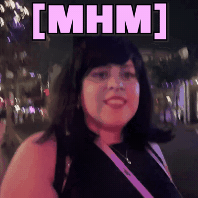A Woman Is Smiling In Front Of A Sign That Says [ Mhm ] On It GIF